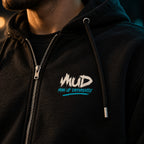 Close-up of the MUD Man Up Differently chest logo on the black MUD After Dark Zip Hoodie, with silver zip and black drawstring