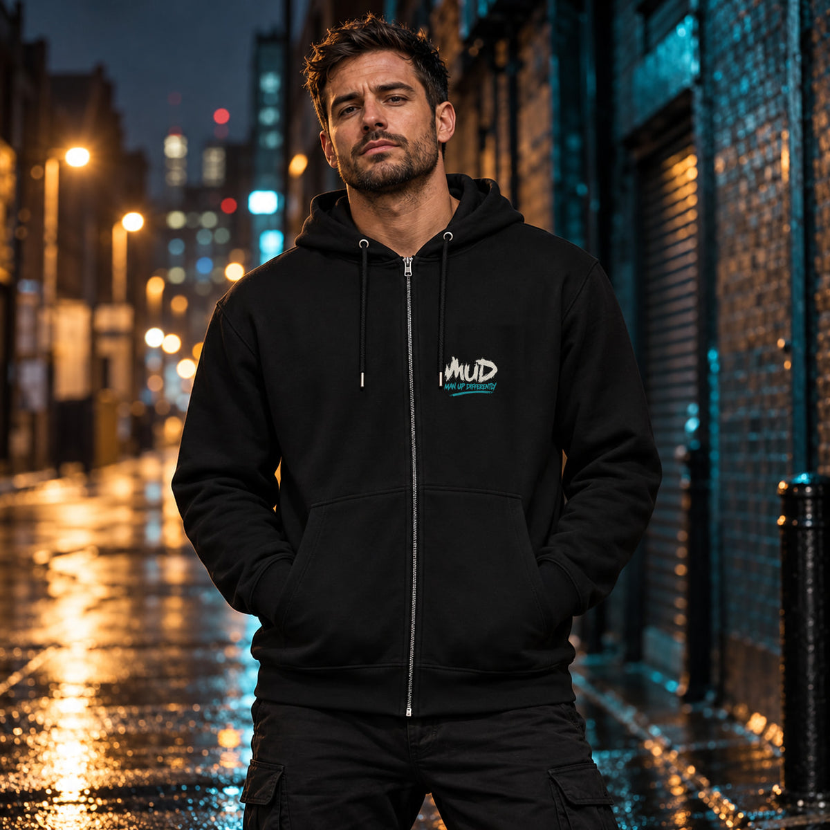 Man wearing the black MUD After Dark Zip Hoodie on a rainy city street at night, with the small MUD Man Up Differently logo on the left chest